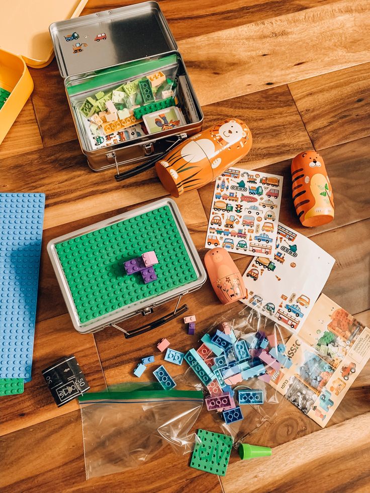 legos and other toys are on the floor next to a tin box with stickers