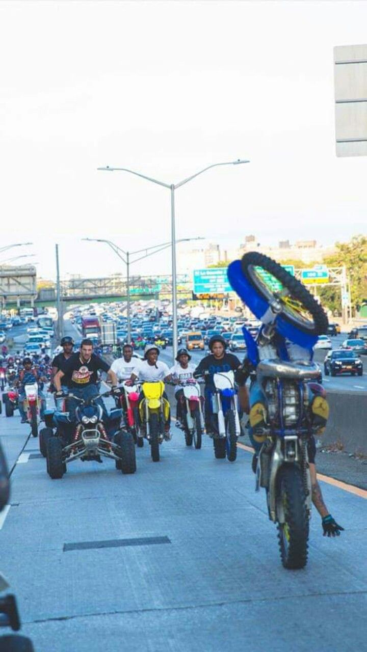 a group of motorcyclists are riding down the street in front of cars