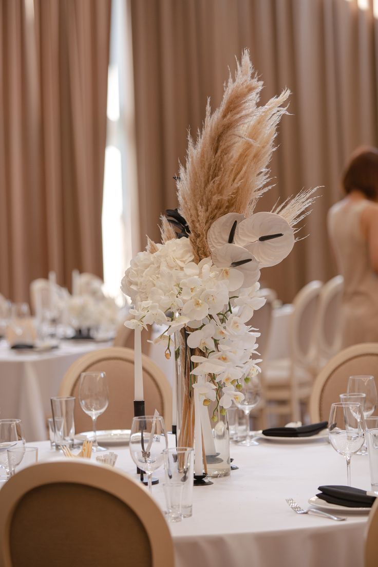 the table is set with white flowers and feathers