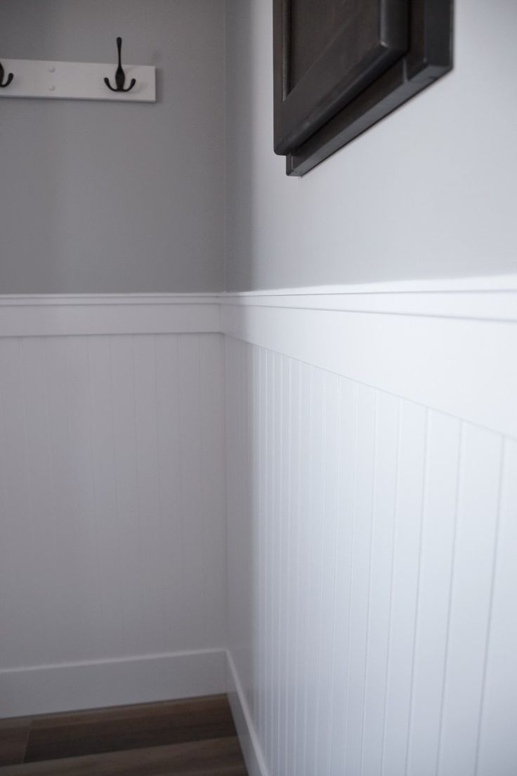 the corner of a bathroom with white walls and wood flooring is painted in gray