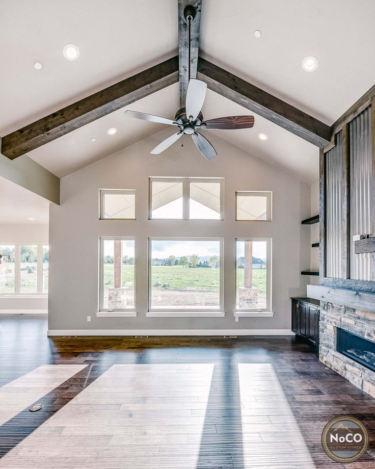 an empty living room with wood flooring and ceiling fan in the middle of it