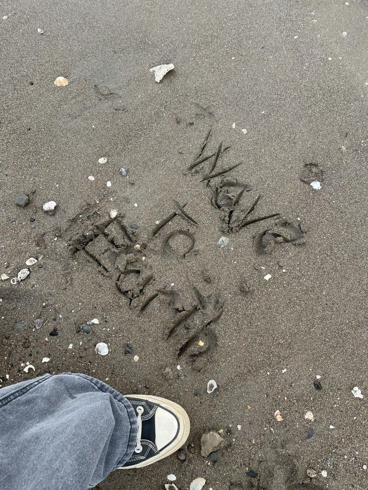 someone's feet in the sand with writing on it