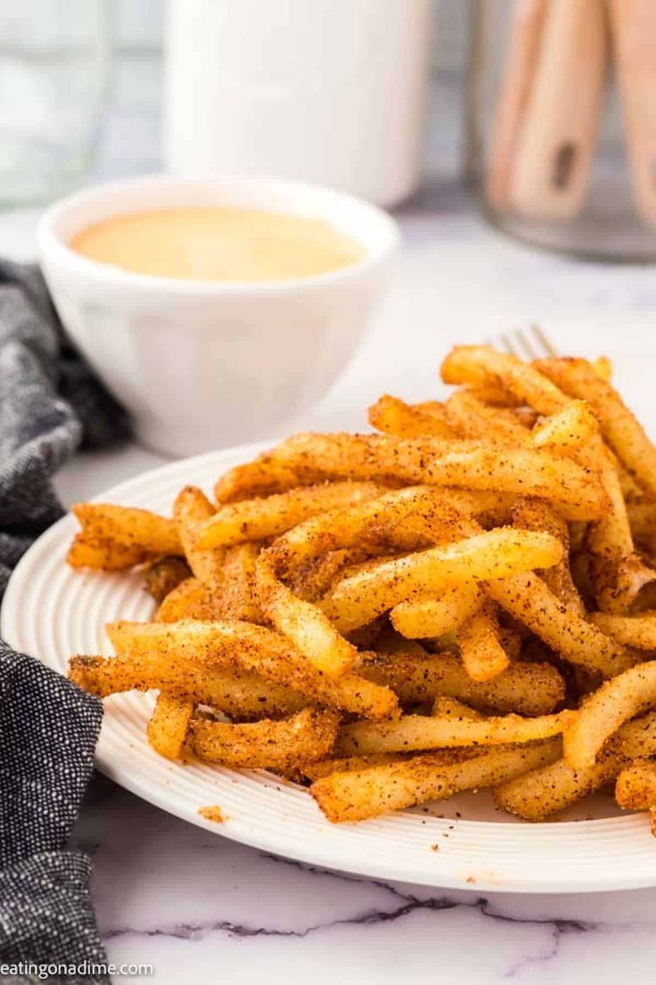 a white plate topped with french fries next to a cup of coffee on a table