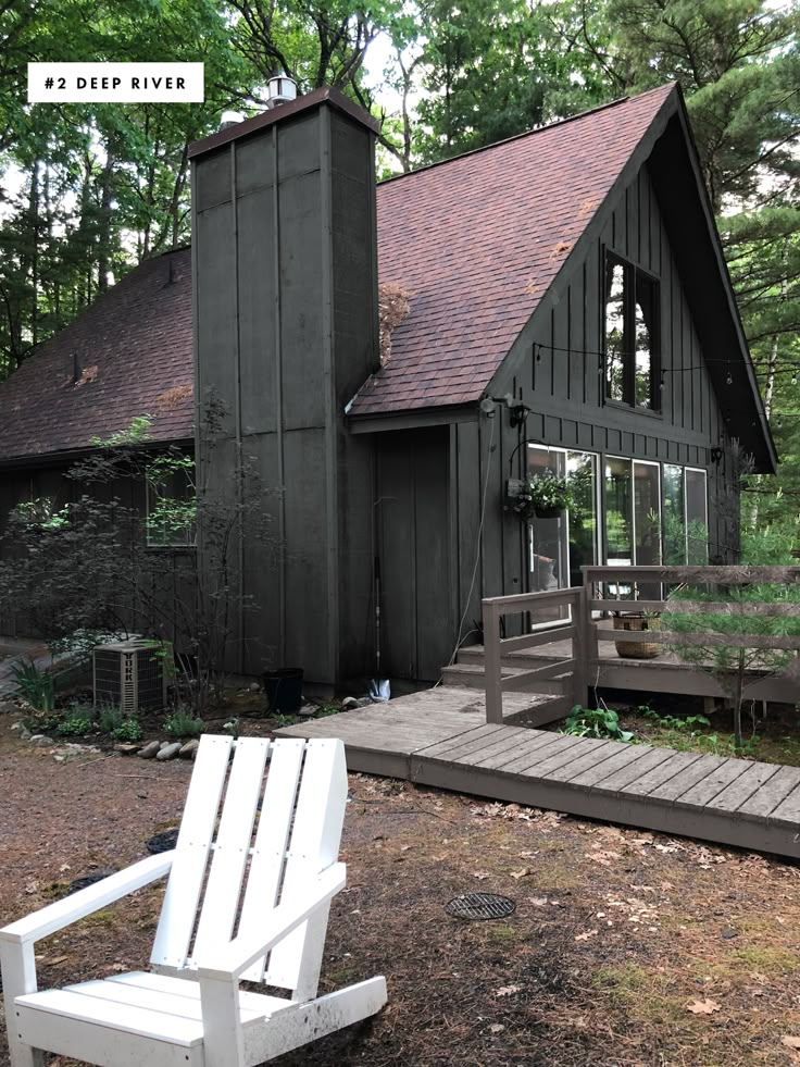 a white lawn chair sitting in front of a black building with a porch and steps leading up to it