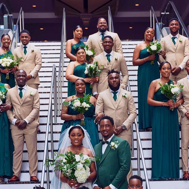 a group of people standing next to each other in front of stairs with bouquets