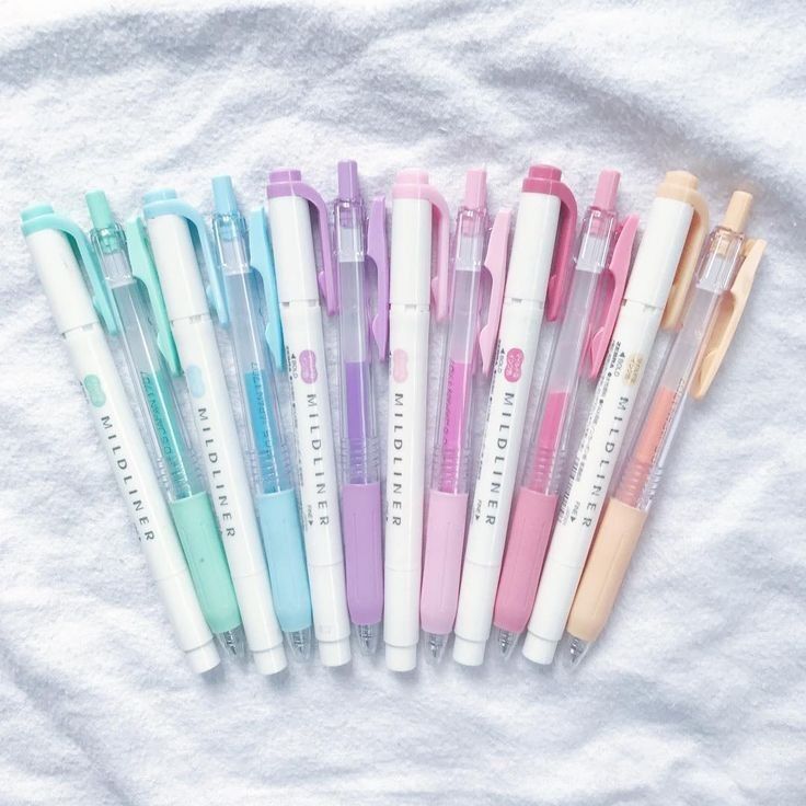 six pens lined up in a row on a white sheet