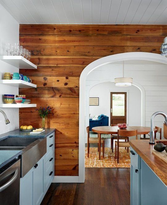 a kitchen with wooden walls and white cabinets