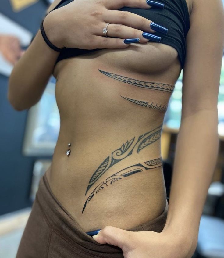 a woman's stomach with tattoos on it and her hand resting on the belly