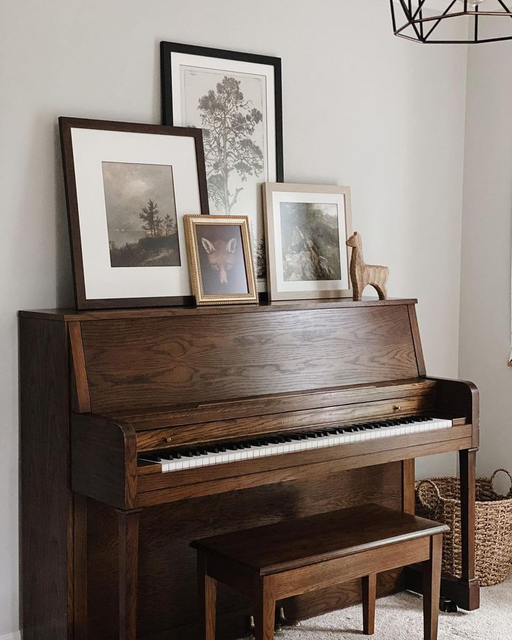 an old piano in the corner of a room with pictures on it and framed photos