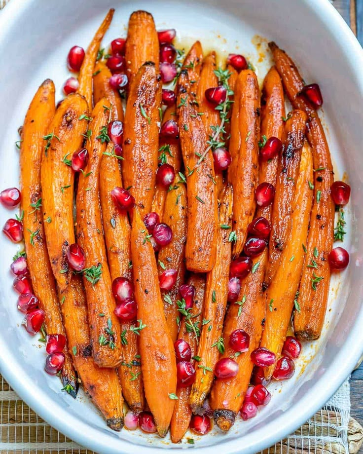 carrots with pomegranate and herbs in a white bowl on a table