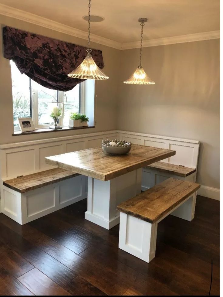 a wooden table and benches in a room with wood flooring, two lights hanging from the ceiling