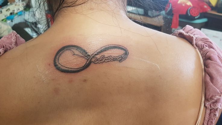 the back of a woman's neck with an infinite sign tattoo on it,