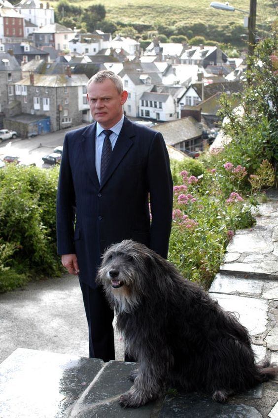 a man in a suit and tie standing next to a dog on top of a rock