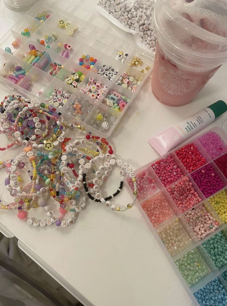 there are many beads on the table next to a cup and some containers with them