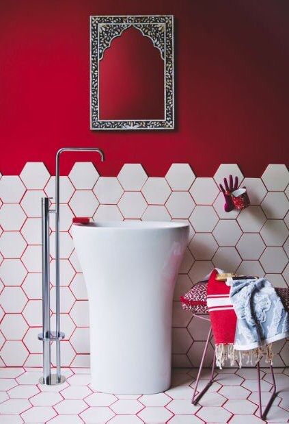 a bathroom with red walls and white tiles on the floor, including a pedestal sink