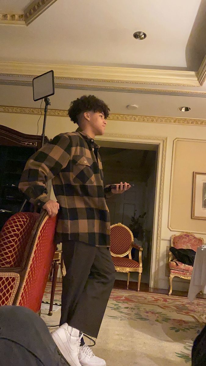 a man standing in a living room next to a red chair