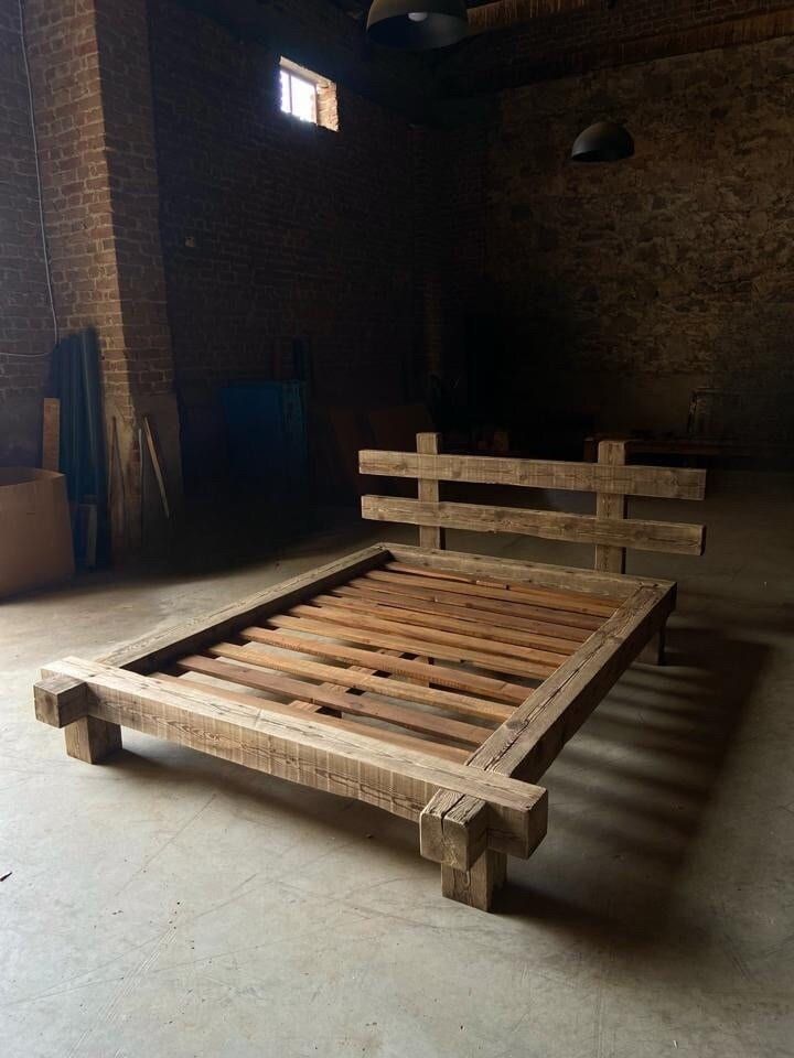 a bed frame made out of wooden pallets in a room with exposed brick walls