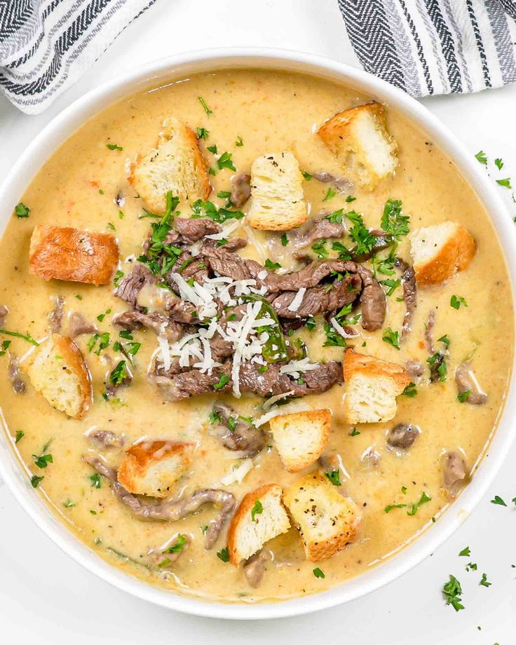 a bowl of soup with meat, potatoes and parmesan cheese