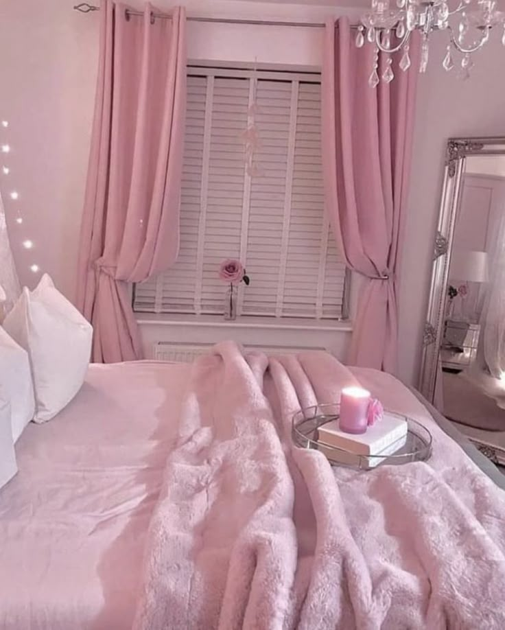 a bedroom with pink bedding and chandelier