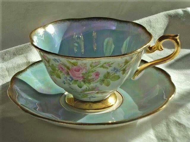 a tea cup and saucer sitting on top of a white tablecloth covered table