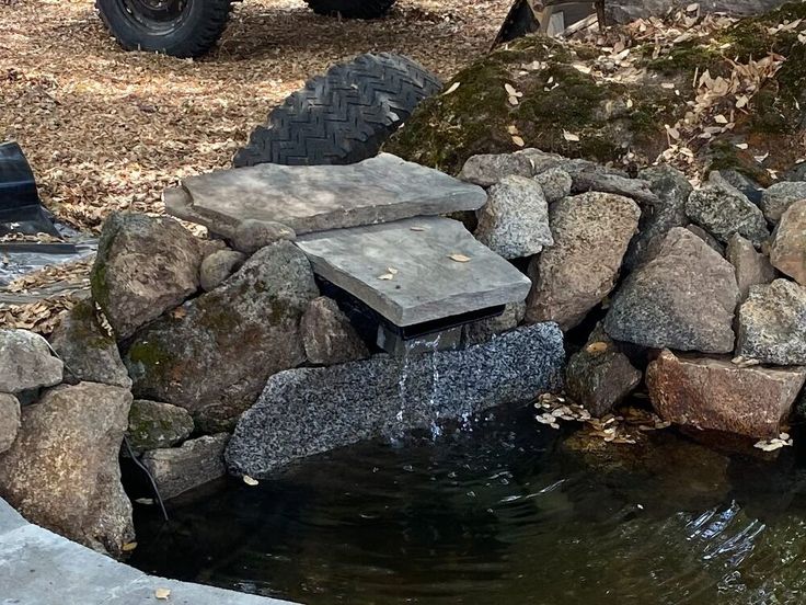 an atv is parked next to a pond with rocks and water flowing from the side