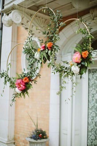 two hoop flower arrangements hanging from the side of a building