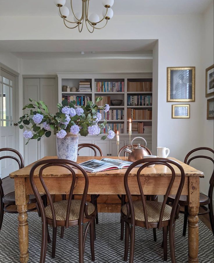 a dining room table with chairs and bookshelves in front of the bookcases