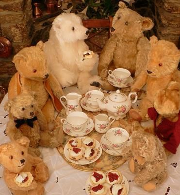 a group of teddy bears sitting around a table with tea cups and saucers