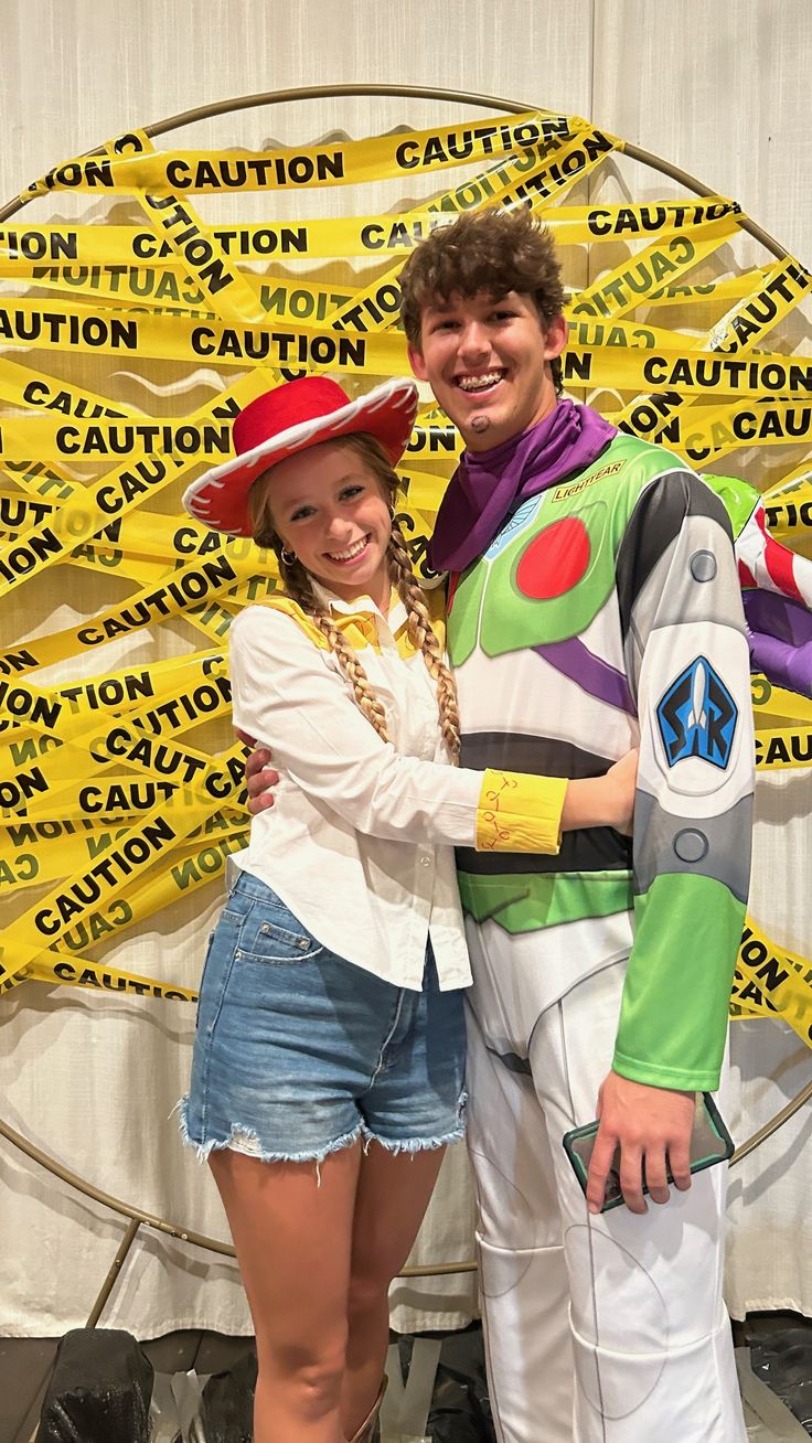 a man and woman dressed up as buzz lightyear from the movie toy story standing in front of a yellow caution sign