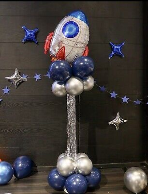 a rocket ship balloon centerpiece with blue, silver and white balloons in the shape of stars