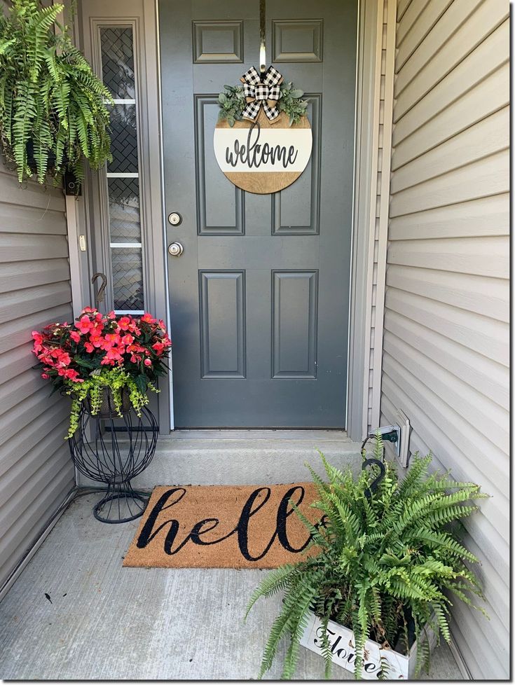 a welcome sign on the front door of a house with potted plants and flowers