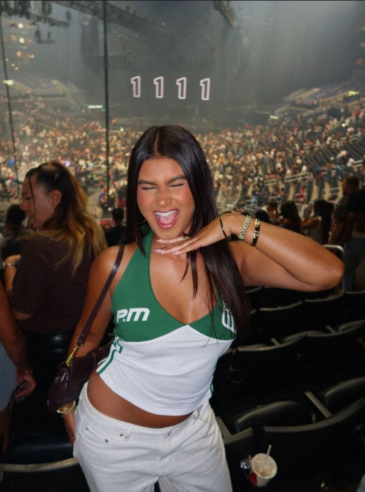 a woman standing in front of an audience at a concert with her hands on her hips