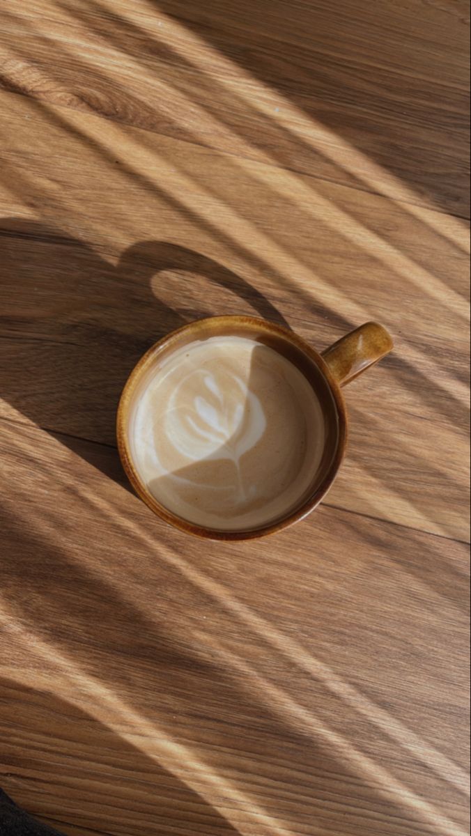 a cappuccino sitting on top of a wooden table