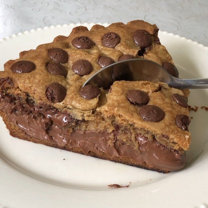 a piece of chocolate chip cookie cake on a white plate with a spoon in it