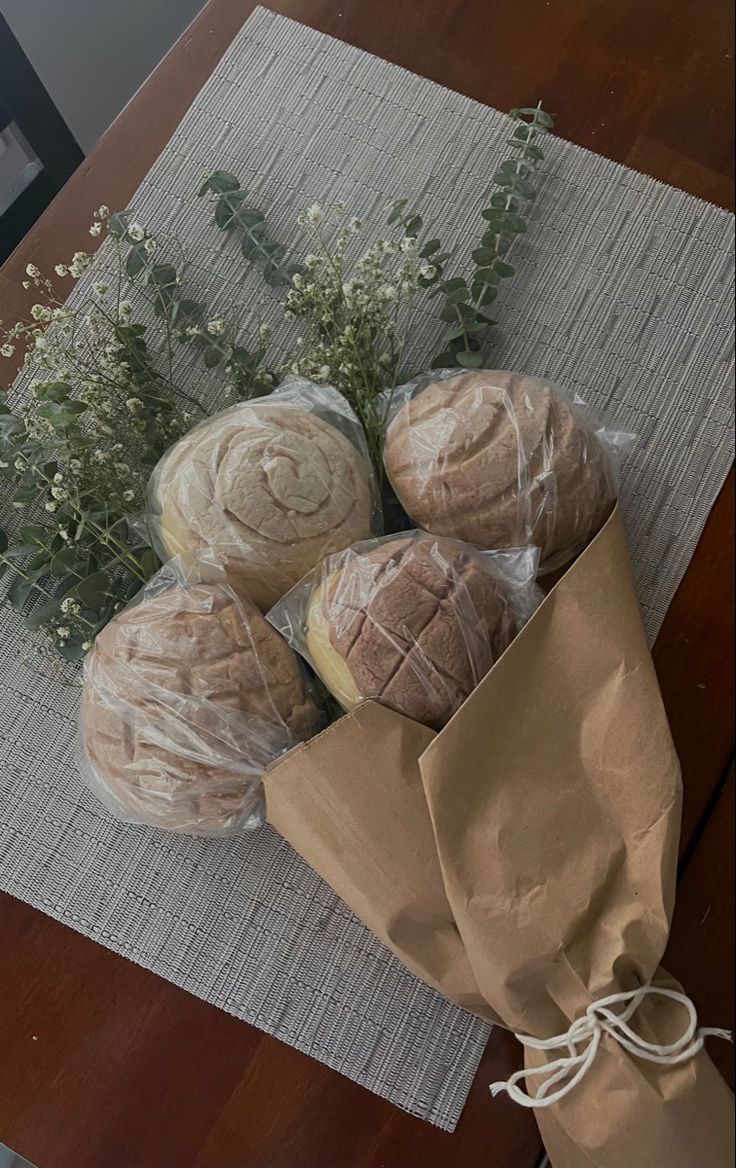 three loaves of bread sitting on top of a table next to a brown paper bag