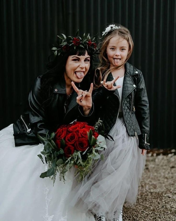 two girls dressed in costumes posing for the camera, one holding a bouquet and the other pointing at the camera