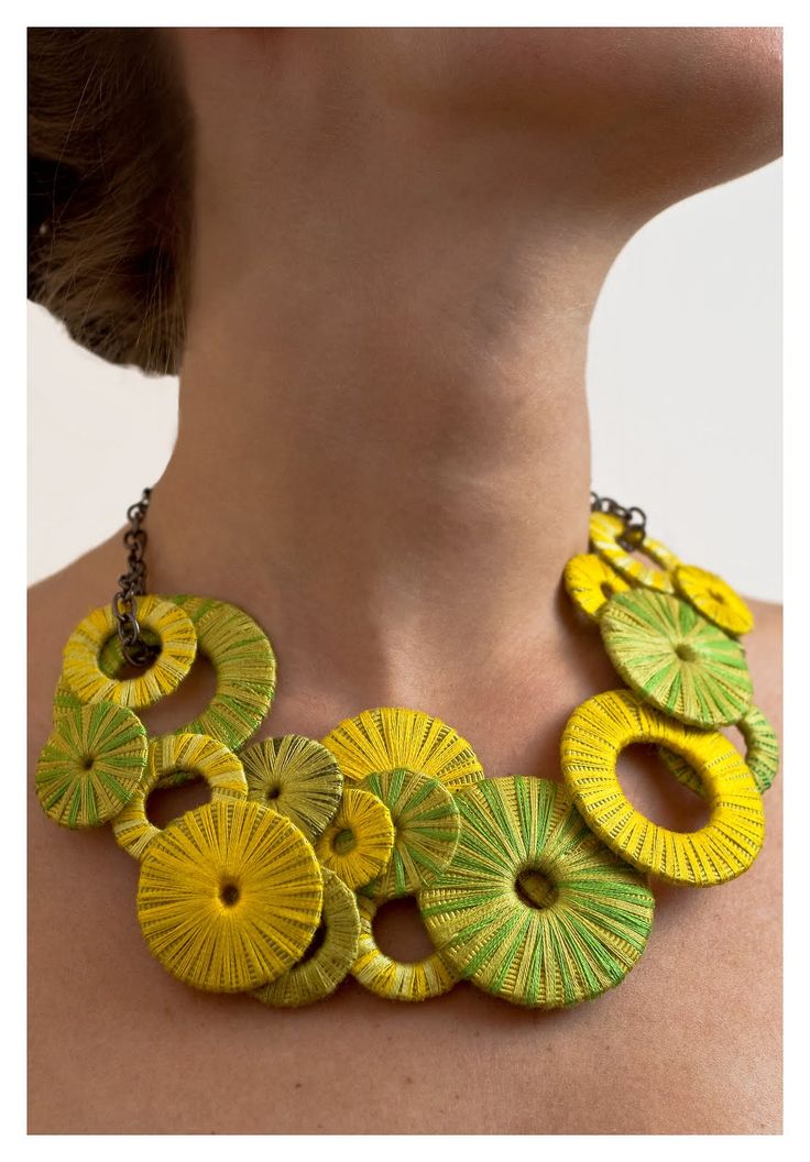 a woman wearing a yellow and green necklace with circular designs on the back of her neck