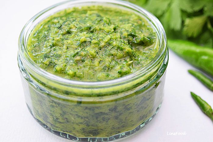 a jar filled with green sauce next to some vegetables