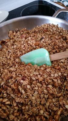 a metal pan filled with granola and a spatula on top of the bowl