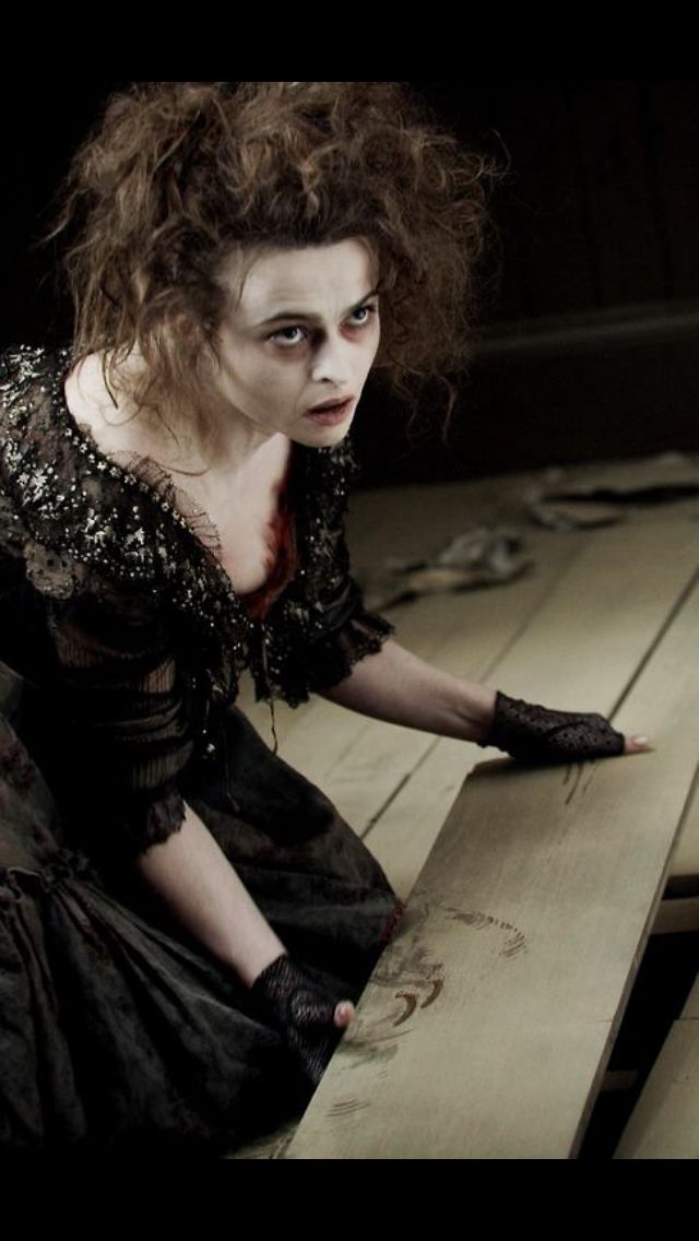 a woman sitting on top of a wooden floor next to a table covered in makeup