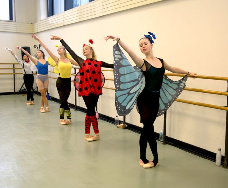 several ballet students are practicing their moves in a dance studio with one dancer dressed as a ladybug and the other wearing a butterfly costume