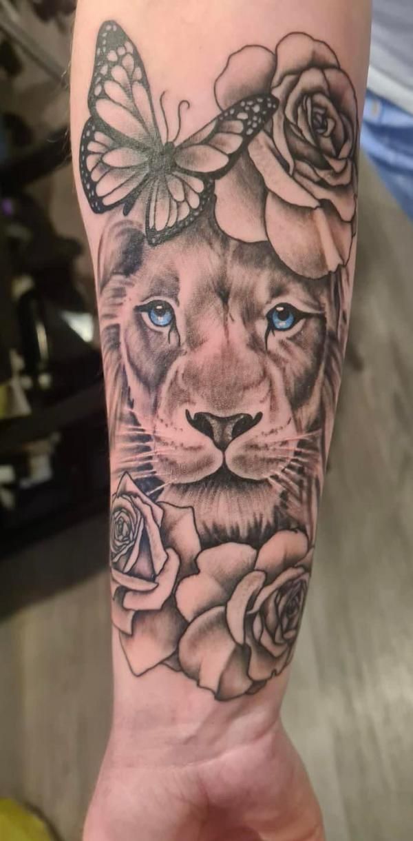 a woman's arm with a lion and roses on it