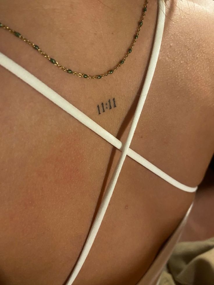 the back of a woman's neck with cross tattoos on her left shoulder and right arm