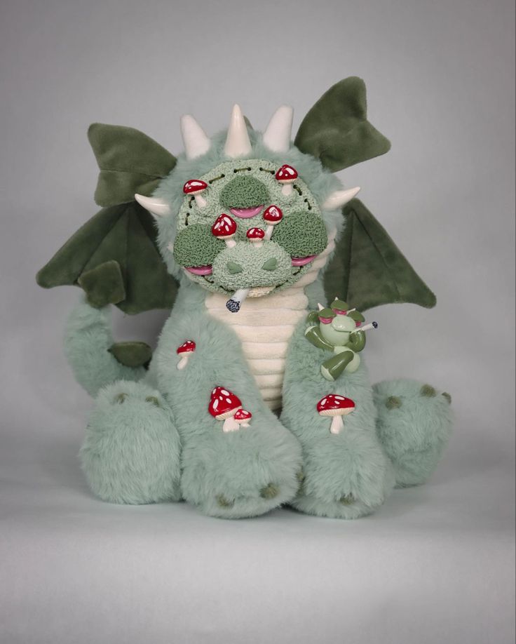 a green stuffed dragon sitting on top of a white table