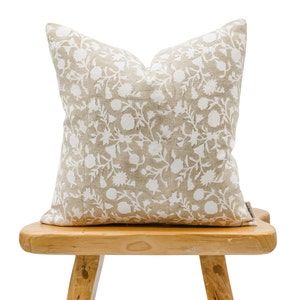 a wooden stool with a pillow on it and a white flowered cushion in the middle