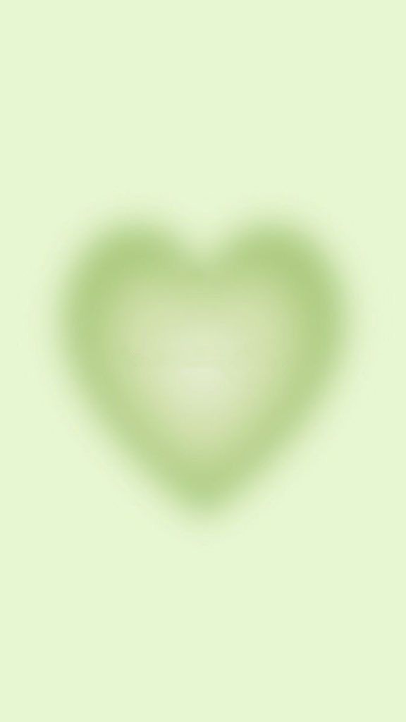 a green heart shaped object on a light green background with the shadow of a person's hand