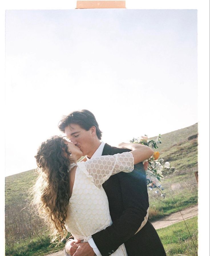 a man and woman are kissing in the grass