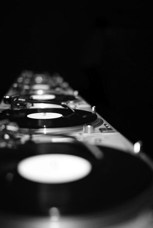 black and white photograph of a row of turntables with vinyl on each side