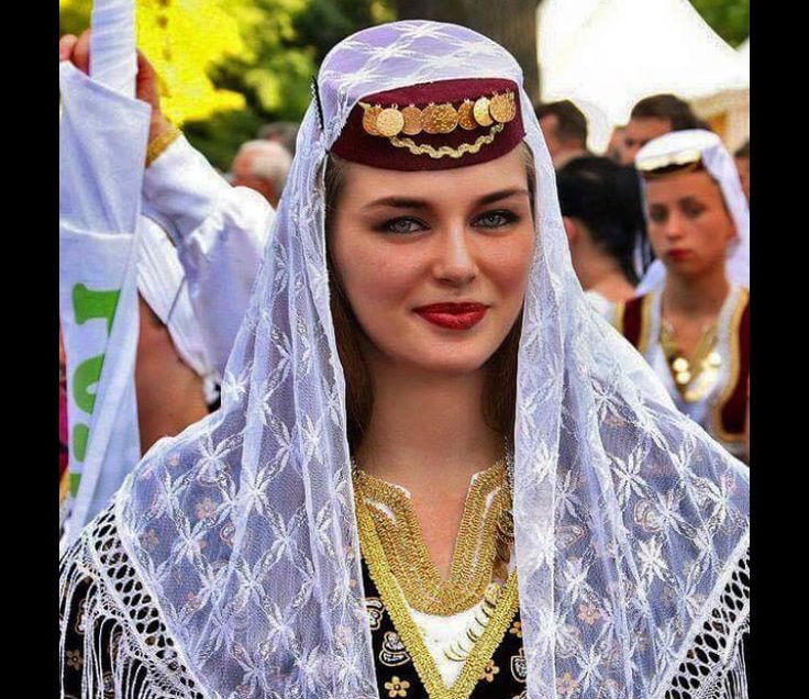 a woman dressed in traditional garb and headdress at an outdoor event with other people