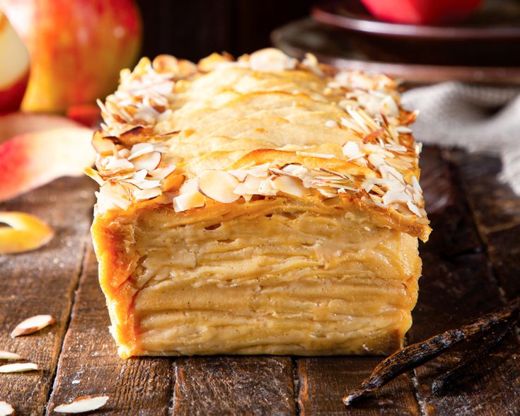 a close up of a pastry on a wooden table with an apple in the background